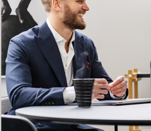 A male 7N staff member sitting beside a black table during a meeting